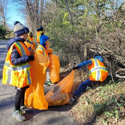 Scouts work together to collect trash during a roadside cleanup